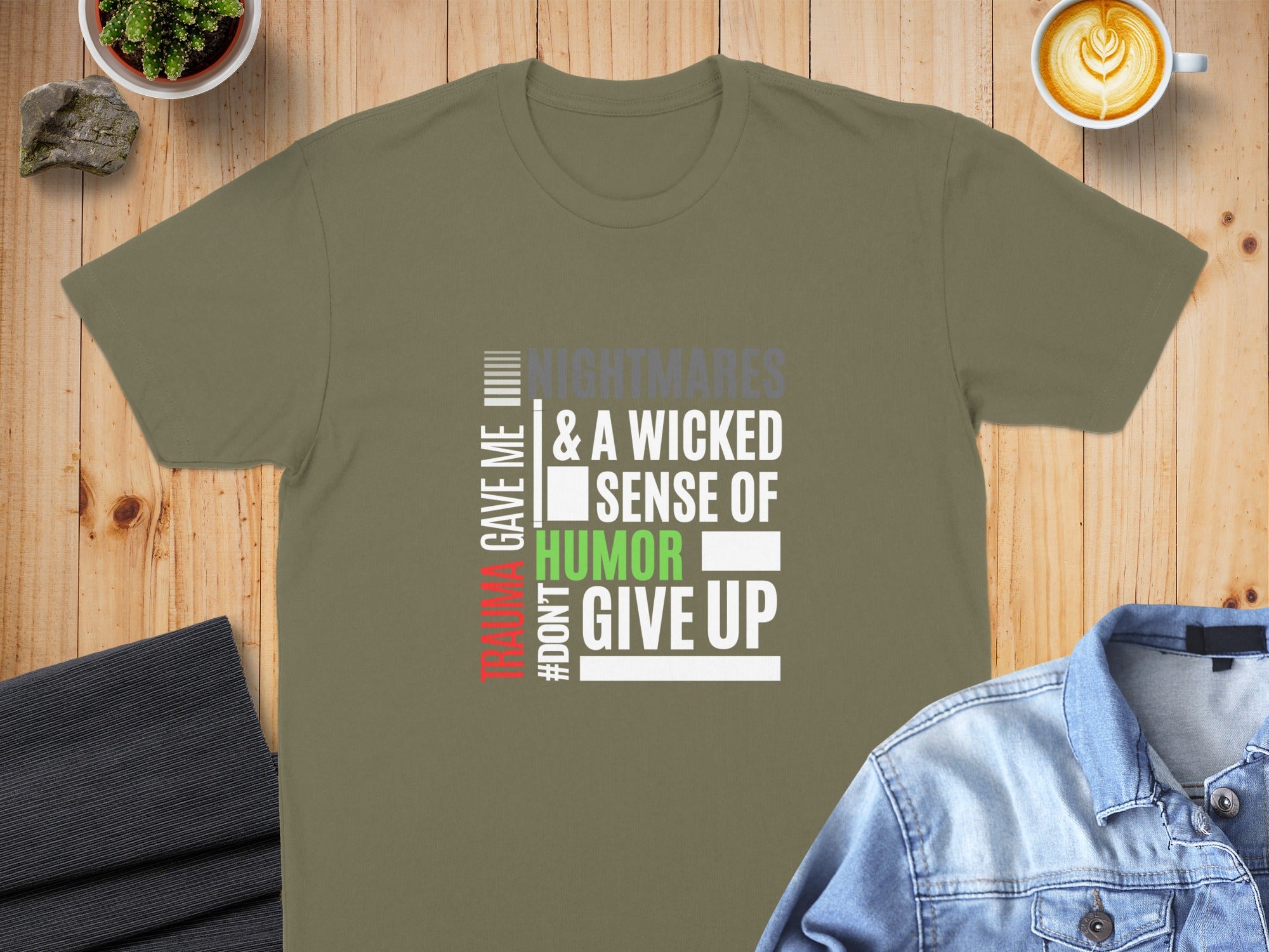 Olive green t-shirt with "TRAUMA GAVE ME #DONT GIVE UP & A WICKED SENSE OF HUMOR" text.