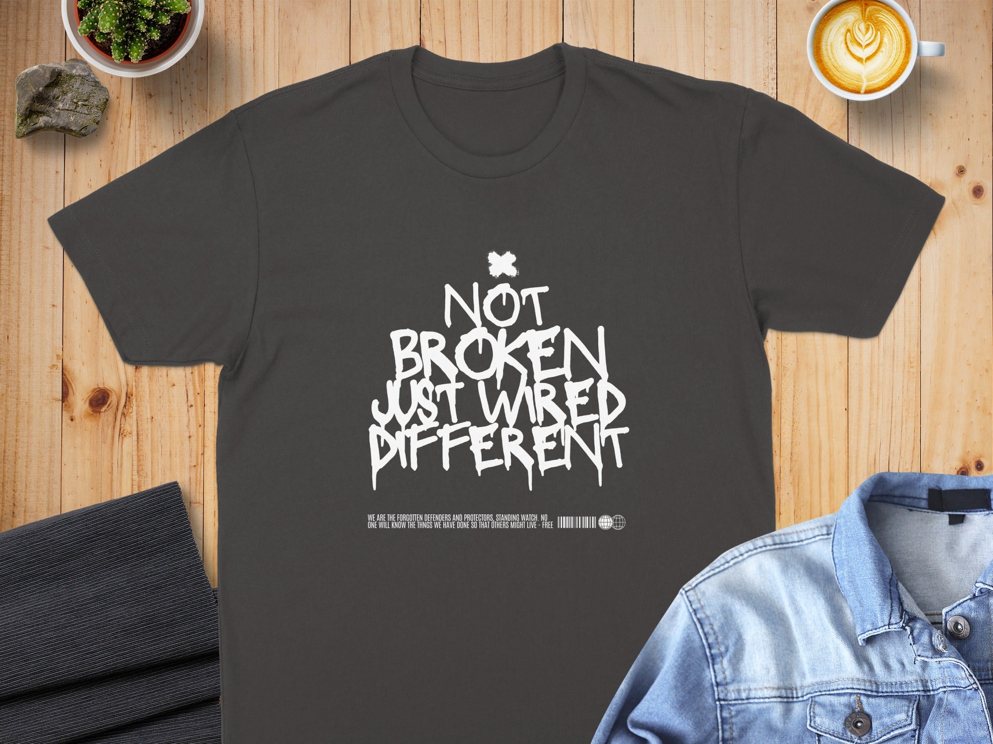 Dark t-shirt with white text "NOT BROKEN JUST WIRED DIFFERENT".