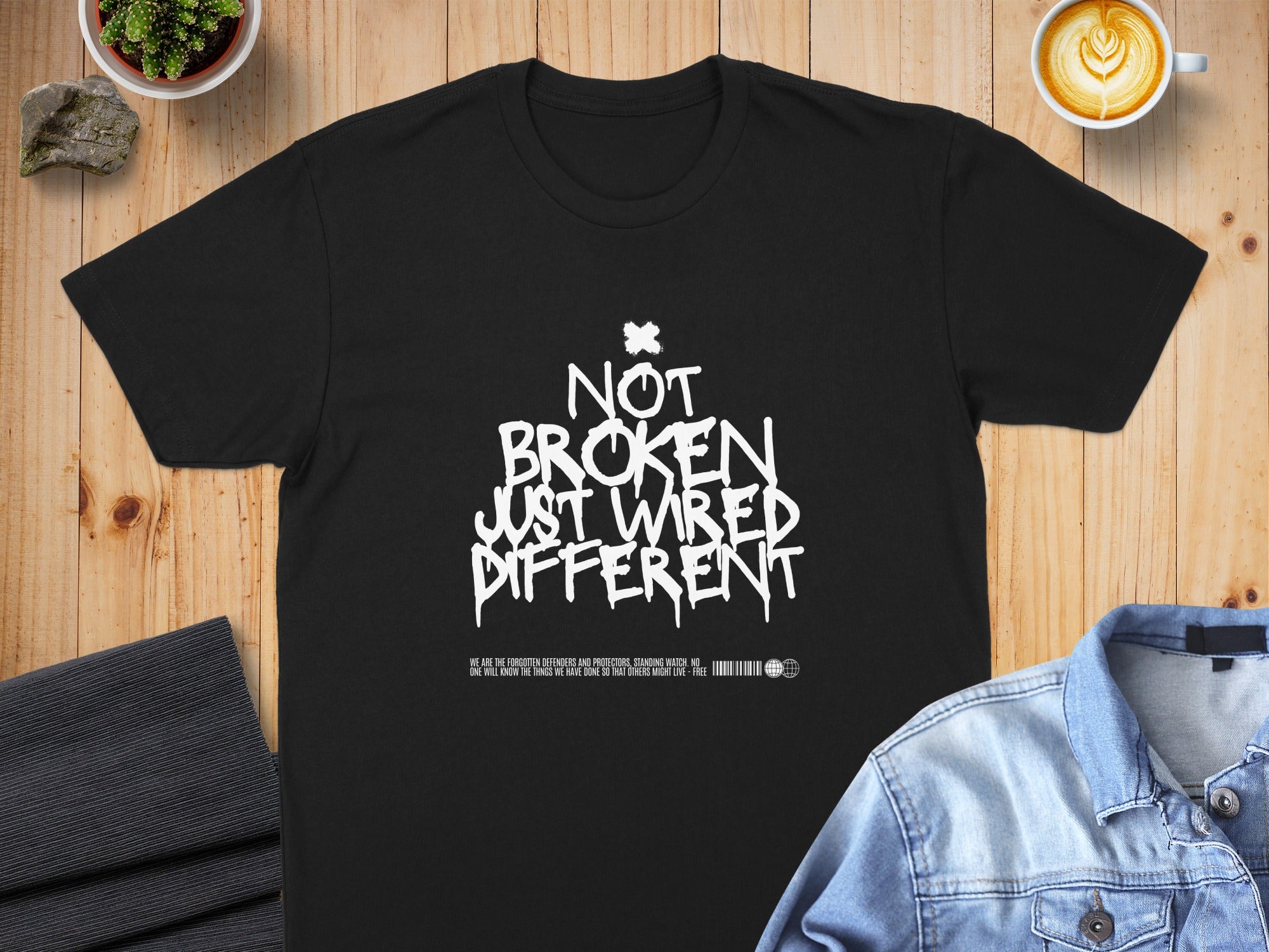 Black t-shirt with "Not Broken Just Wired Different" in white graffiti text.