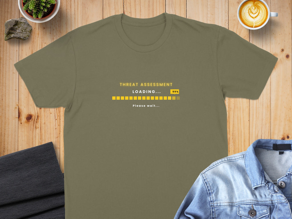 Olive green t-shirt with "THREAT ASSESSMENT LOADING... 99%" progress bar.