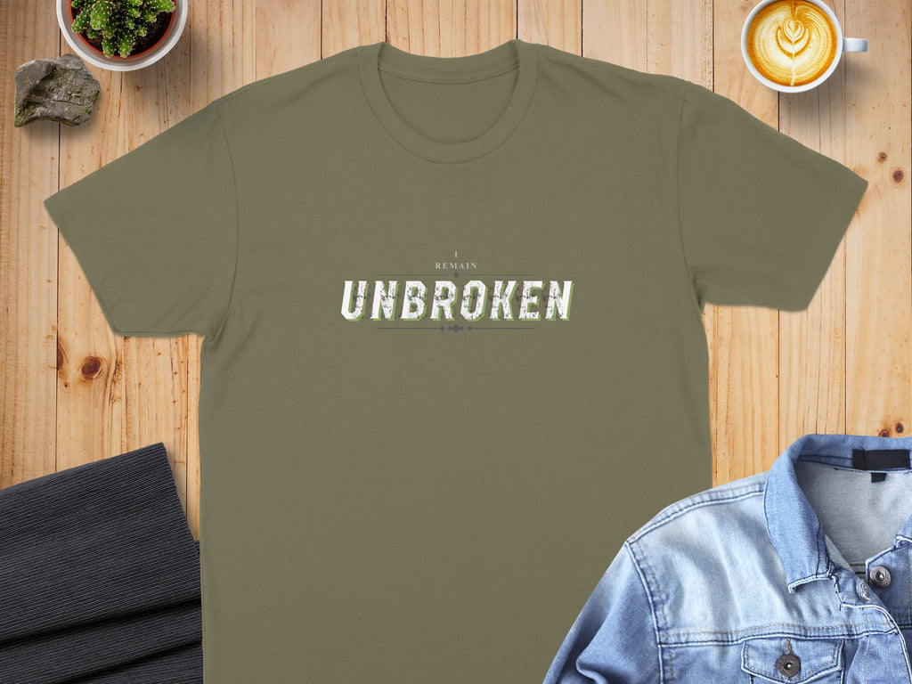 Green t-shirt with "I REMAIN UNBROKEN" text, styled on a table.