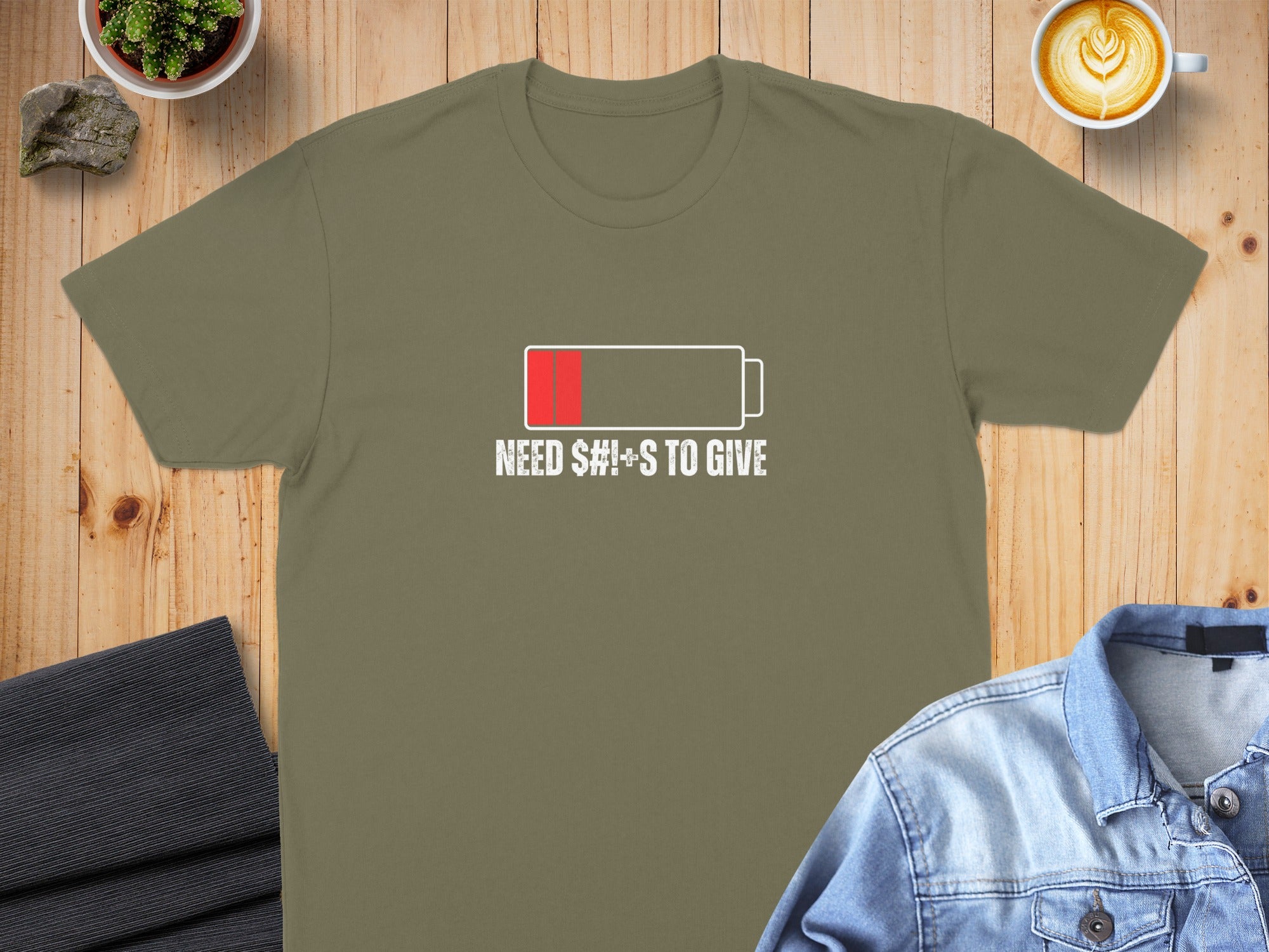 Khaki t-shirt with "Need $#!+s to give" battery graphic.