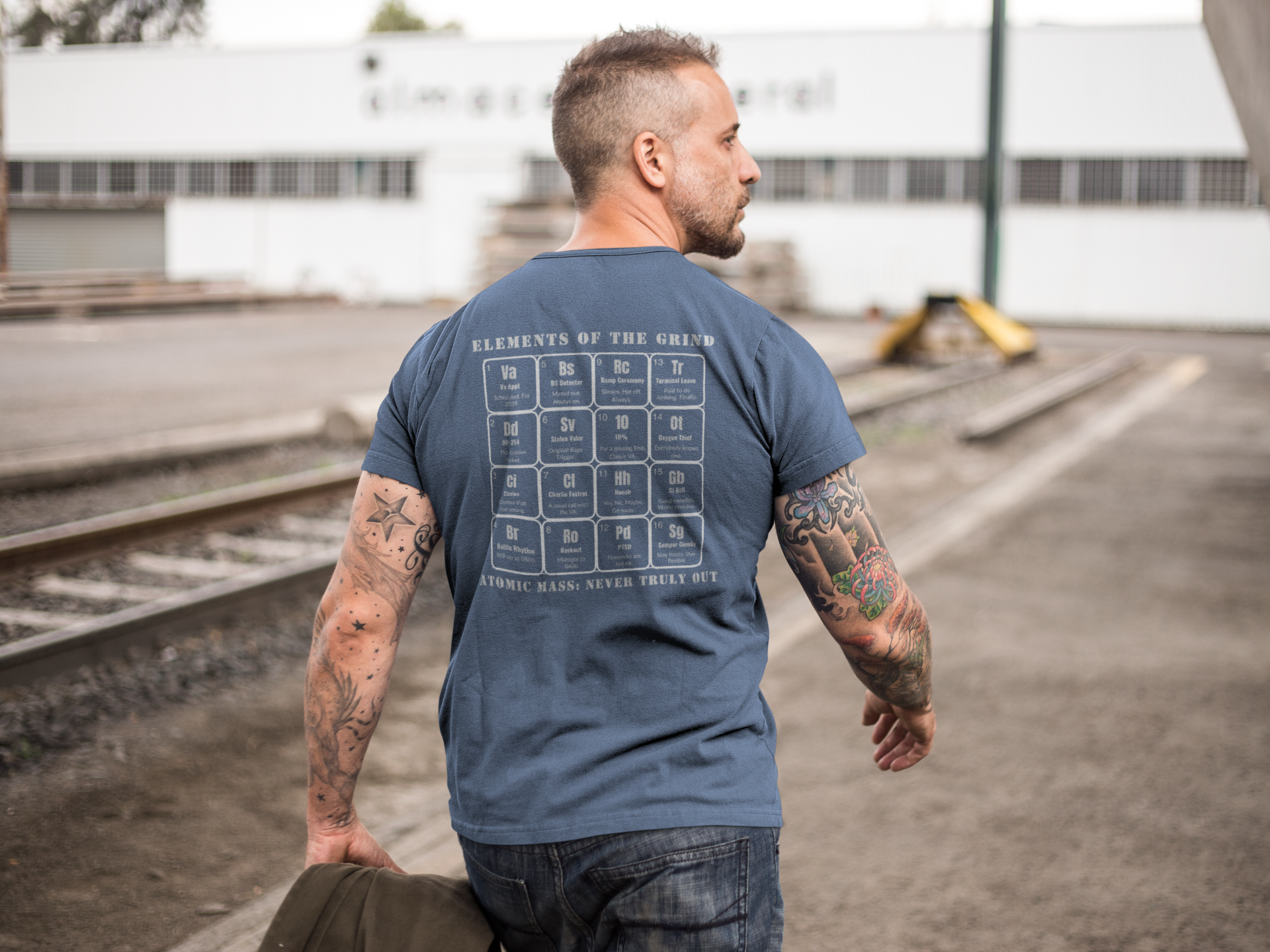 mid aged , walking near train tracks, wearing navy t-shirt, elements of the grind. tactical pause apparel.
