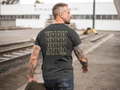 Middle-aged man walking near train tracks, wearing a black t-shirt, elements of the grind. Tactical pause apparel.